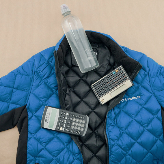 a jacket laid out on a table with a clear water bottle and two calculators