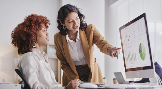 two woman looking at finance data on computer screen