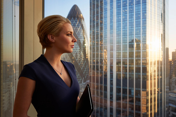 A businessperson staring out of an office window looking out at the London city skyline